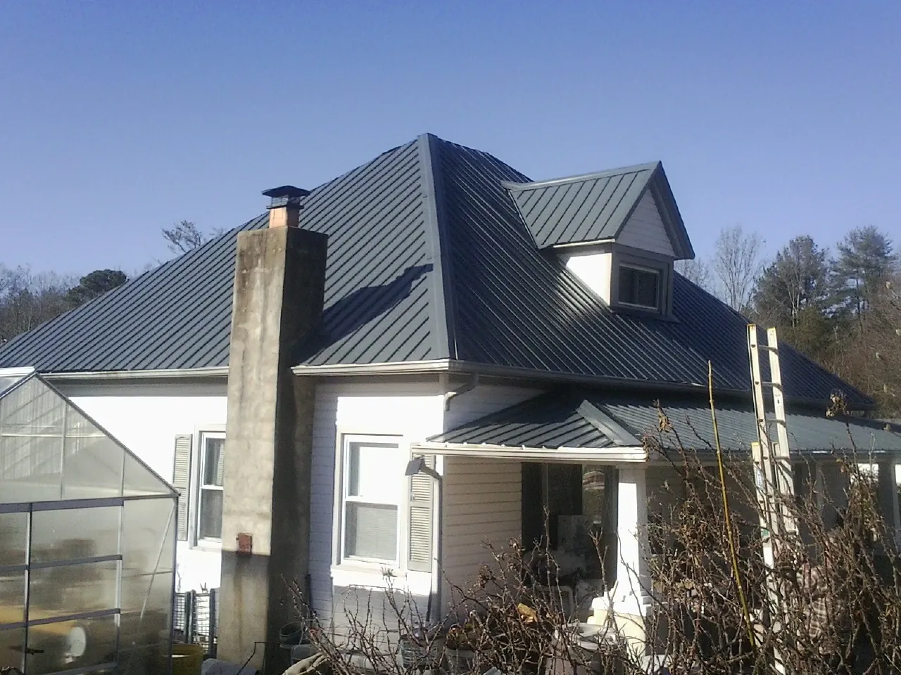 Dark blue standing seam metal roof on a white farmhouse with dormer — Slate & Tile Roof Repair by Roofing Brothers in Copenhagen