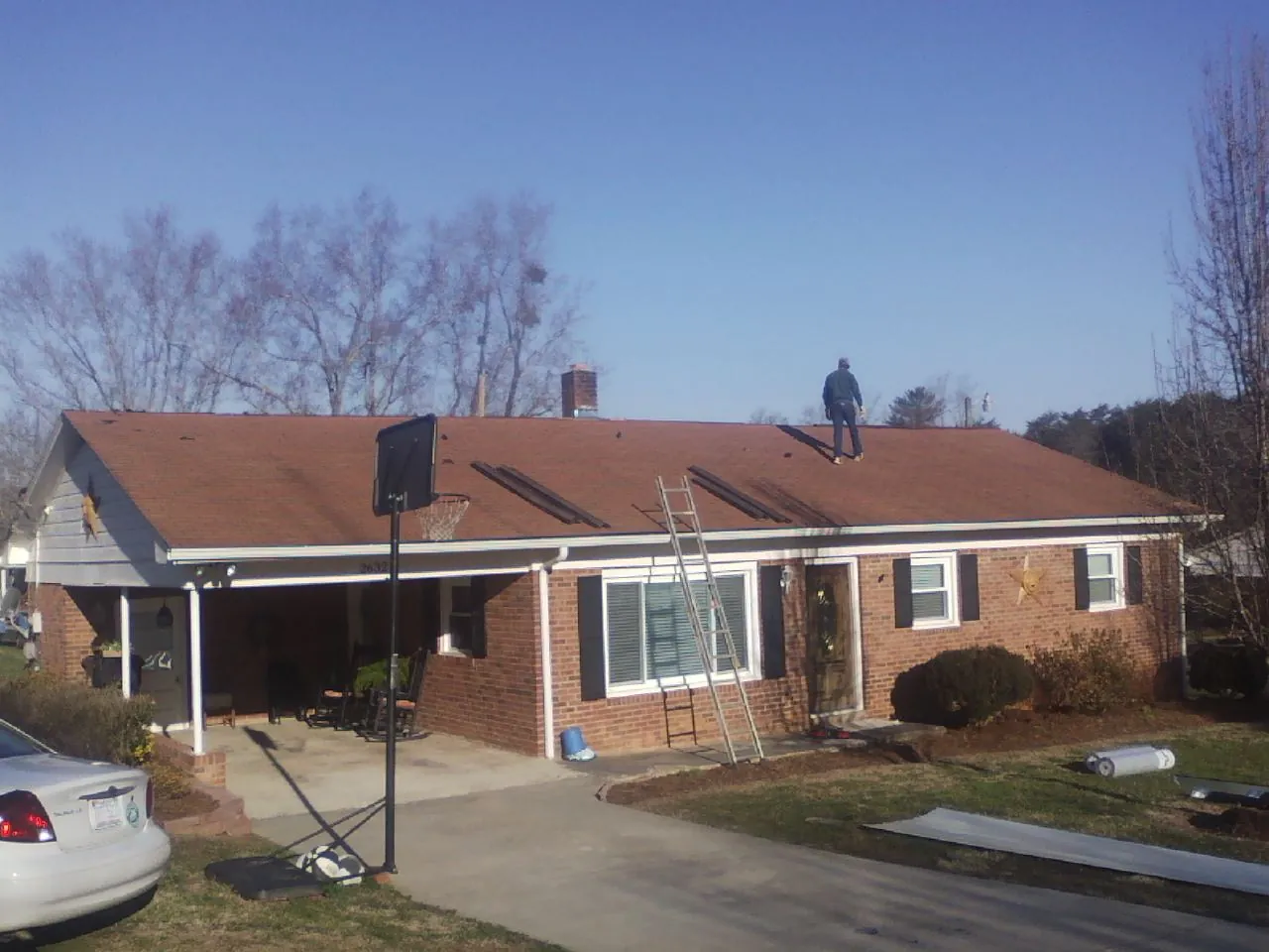 Roofer stripping a shingle roof on a brick ranch before metal panels in Copenhagen