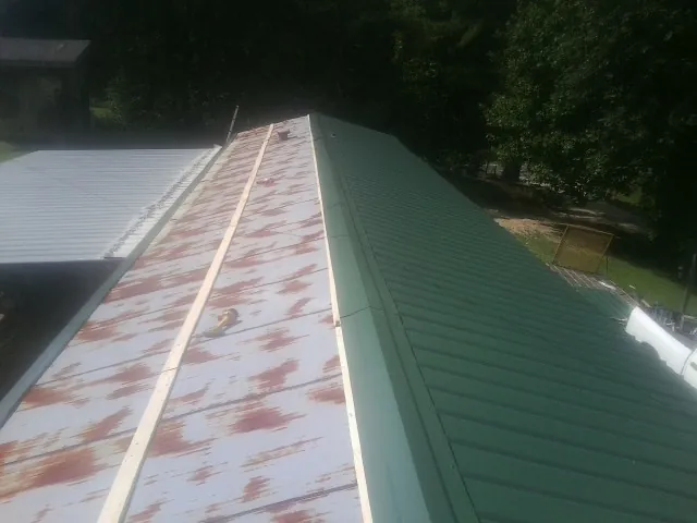 Old rusted panels beside newly installed green metal roofing — Wind Damage Roof Repair by Roofing Brothers in Copenhagen