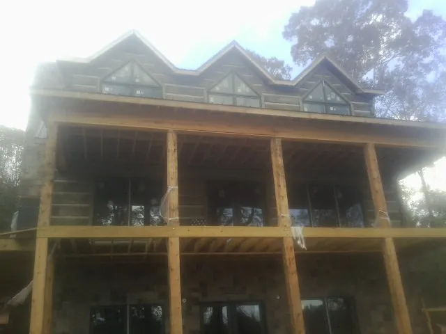 Dormers and porch framing on a large log home under construction — Roof Coating work by our crew in Copenhagen