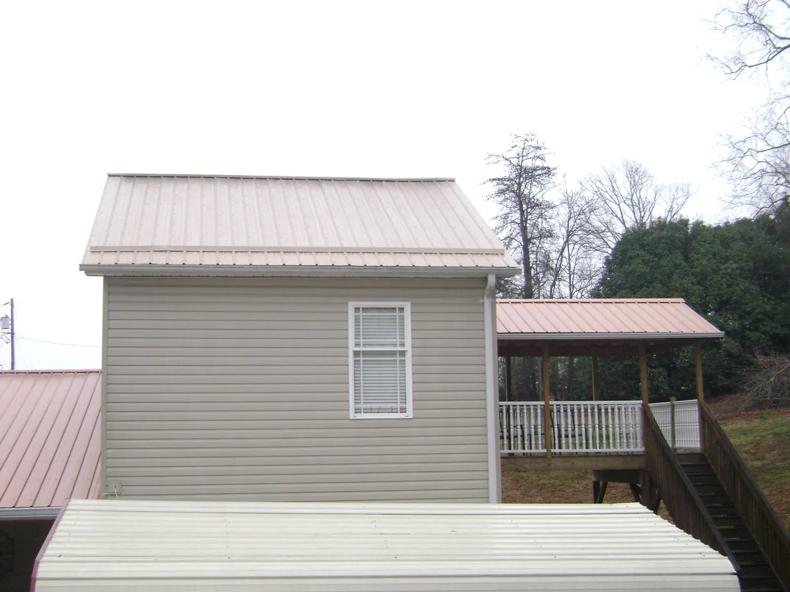 Tan metal roofs on a two story addition and attached porch, from a Roof Replacement job in Copenhagen