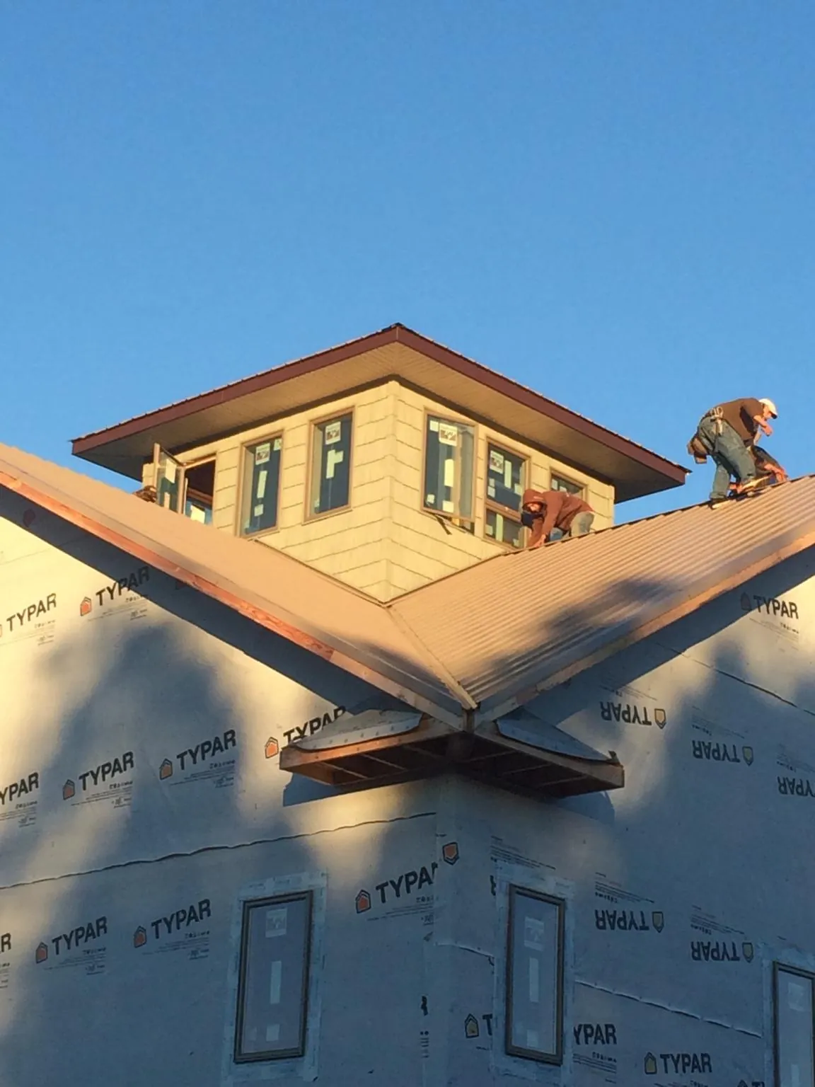 Roofers working around a rooftop cupola on a new metal roof at sunset — Roof Waterproofing in Copenhagen by Roofing Brothers